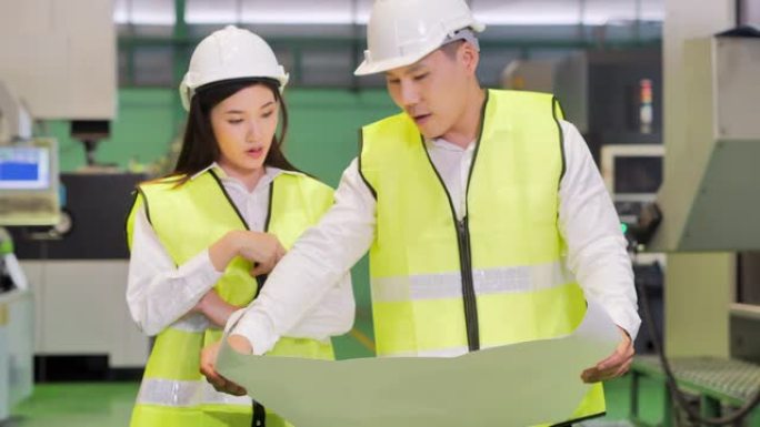 男性和女性工业工程师站在重工业制造基地看项目蓝图。技术，工业，科学，创新，工业4.0，妇女在STEM
