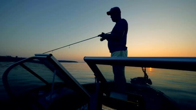 一个人在日落背景上抓鱼，特写。