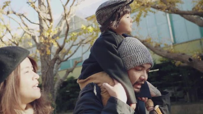 小男孩在公园里骑在父亲的肩膀上
