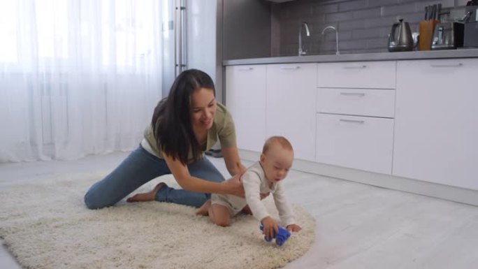 亚洲妈妈在家里的地毯上玩婴儿