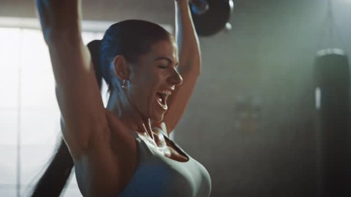 运动美女在健身房用杠铃顶起。华丽的女性专业健美运动员在硬核训练设施中进行举重锻炼。放大