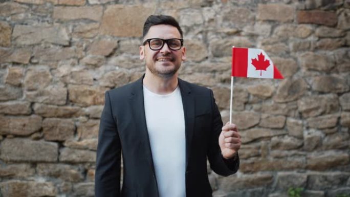 长着胡须的英俊男子独自站在户外挥舞着加拿大国旗的肖像