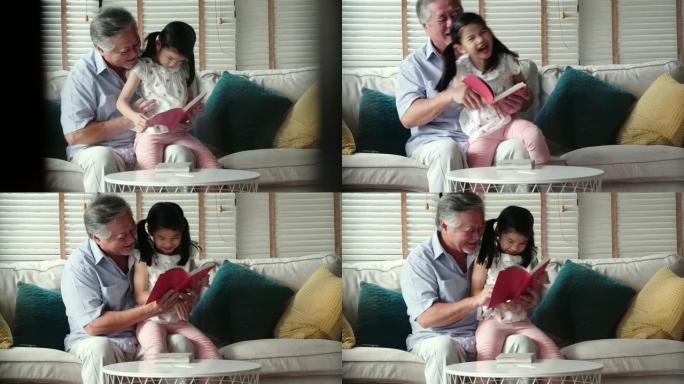 快乐的小女孩和爷爷在家读故事书。香港的家庭