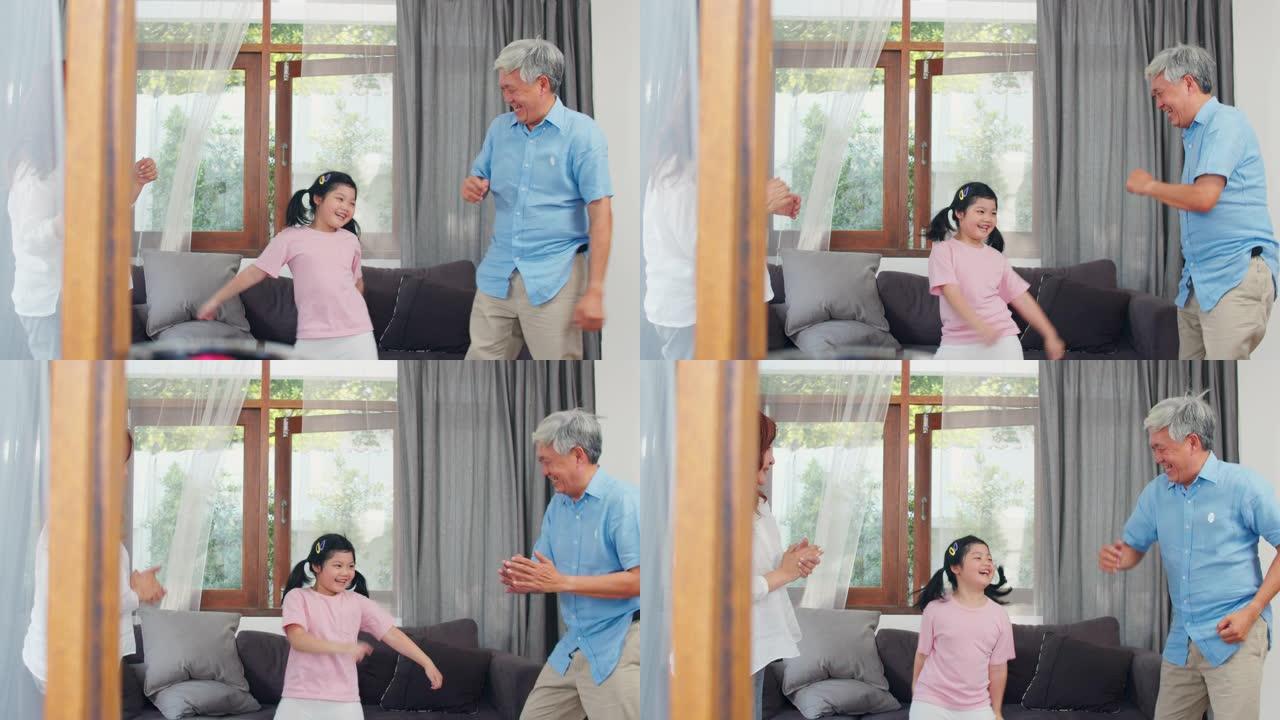亚洲祖父母和孙女在家里一起听音乐和跳舞。高级中国人，爷爷和奶奶开心地与客厅概念中的年轻女孩一起度过家