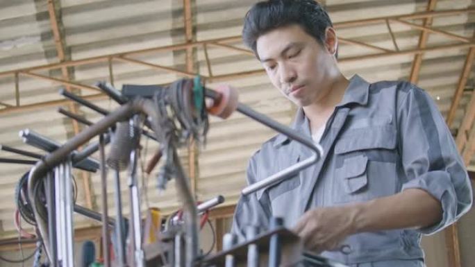 专业男子机械师进入车架并在汽车维修中寻找工具。
