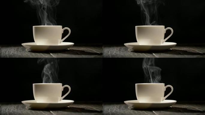 一杯热咖啡。蒸汽从站在木桌上的白色碟子上的咖啡杯中流出。黑色背景特写镜头，UHD