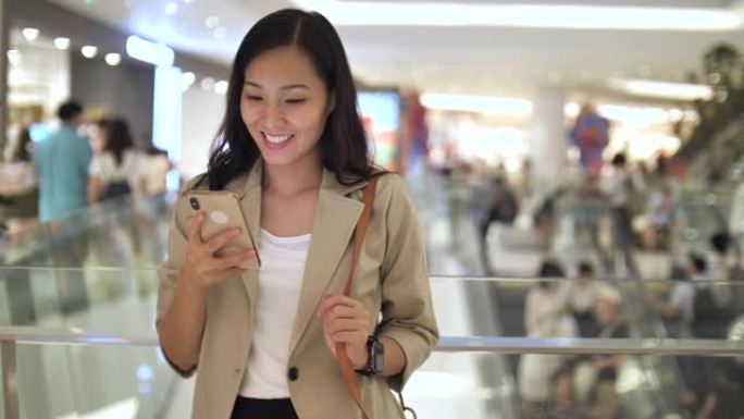 亚洲妇女在购物中心使用手机
