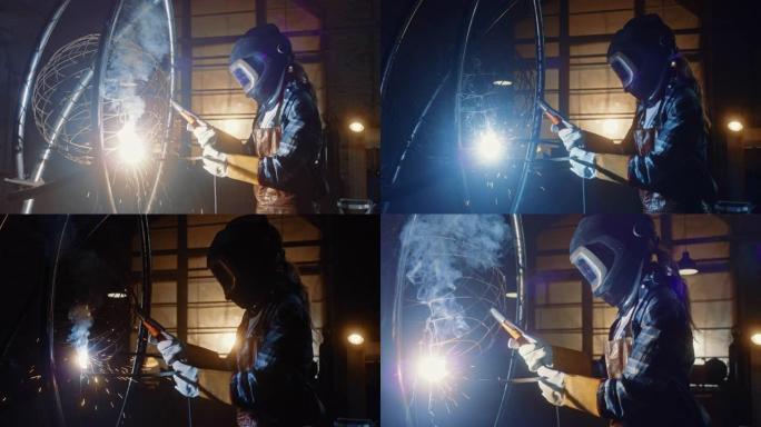美丽的女艺术家正在黑暗的工作室里焊接一个残酷的金属雕塑。假小子女孩用火花擦亮金属管。当代制造商创造抽