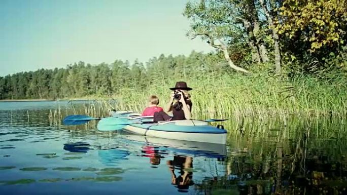 母子俩在湖上划皮划艇。妈妈拍照