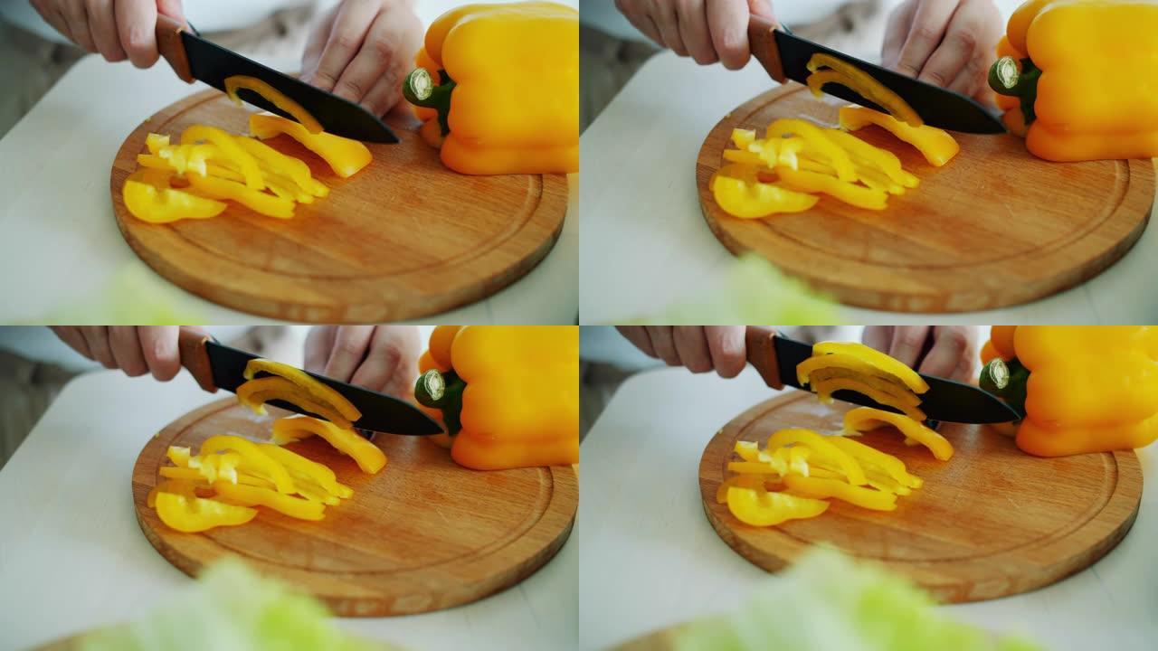 女性用刀在木板上切黄椒做素食沙拉