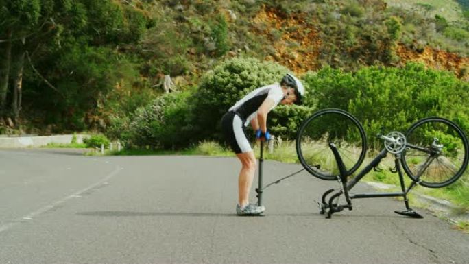 中年运动员在4k乡村公路用自行车泵泵送自行车轮胎