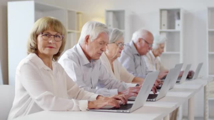 老年妇女在计算机课上看着相机