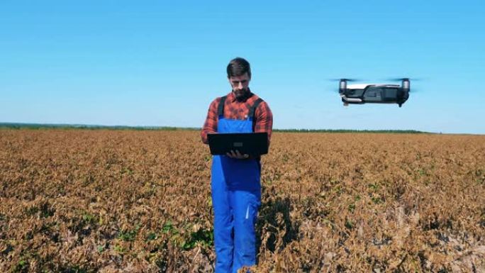 农业学家正在褪色的田野中导航无人机