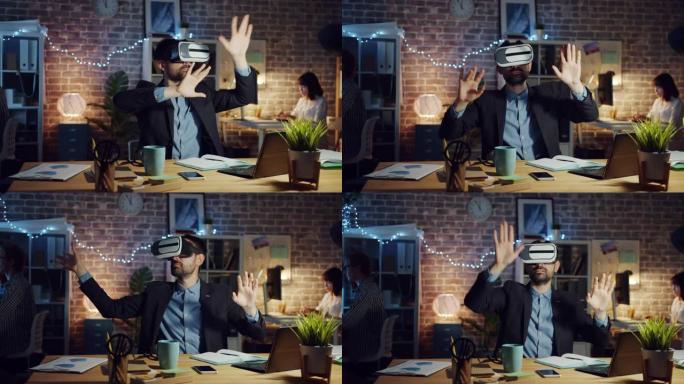 男人在黑暗的办公室里使用虚拟现实眼镜移动手臂坐在桌子上