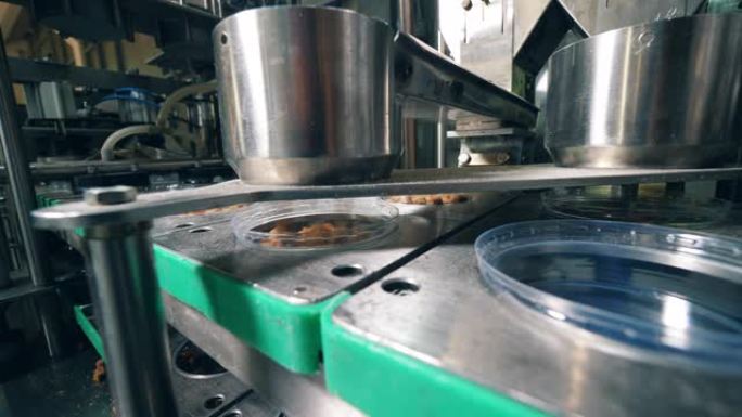 金属装置在工厂用干面包饼干填充塑料容器。