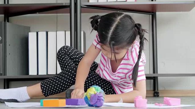 儿童生活中的一天: 微笑的小女孩在家里用橡皮泥做艺术和手工艺。
