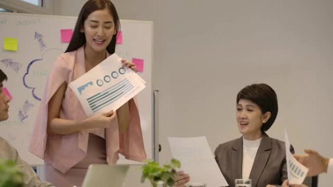 提交工作计划业务报告的迷人亚洲女性在公司会议上向她的团队提交论文，在办公室简报会上做文书工作的多元化