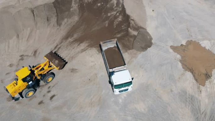 黄色拖拉机在采石场用沙子装载机器。采矿业设备。