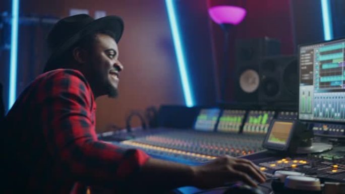 在音乐录音棚工作的音频工程师肖像，使用调音板创造现代声音。成功的黑人艺术家音乐家在控制台工作。开心，