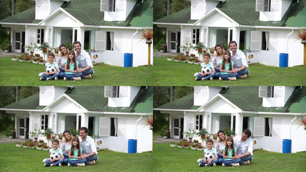 后院的美丽家庭坐在草地上，对着镜头微笑，非常开心