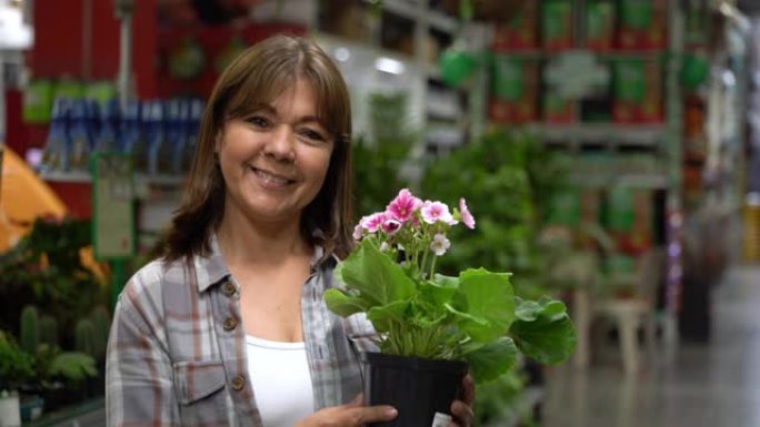 快乐的拉丁美洲妇女在五金店或花园中心购买植物