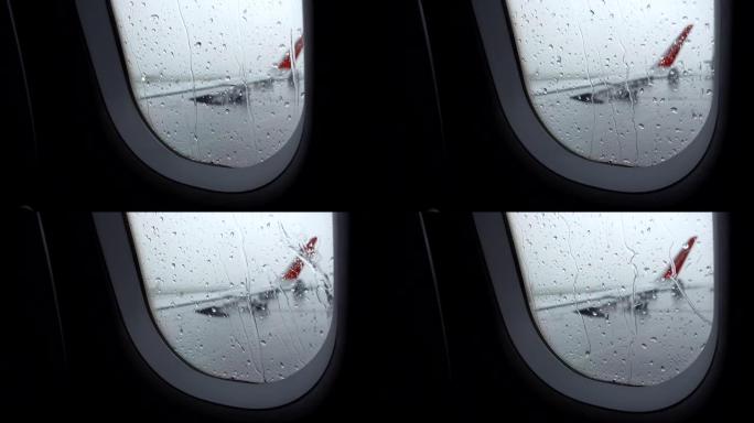 机场因阴雨恶劣天气而延误，飞机窗户上有机翼的雨滴