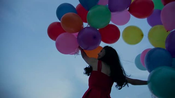 拿着天空背景的气球的女孩在慢动作。