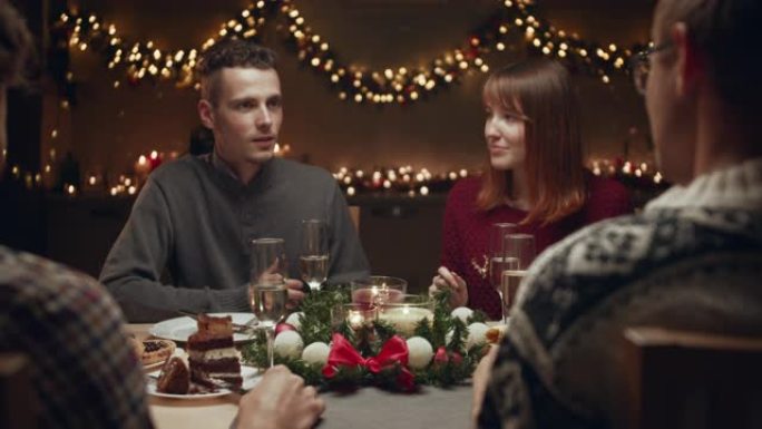 朋友庆祝圣诞节。他们坐在圣诞餐桌旁，在舒适的家庭环境中交流。