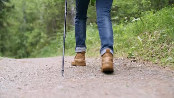 女性徒步旅行者的腿用电线杆行走