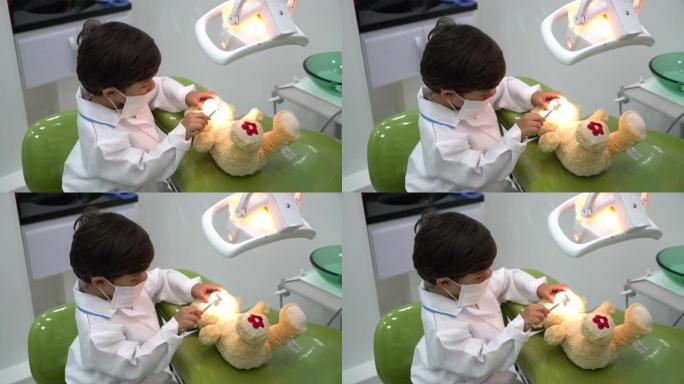 可爱的小男孩假装检查他的泰迪熊牙齿的高角度视图