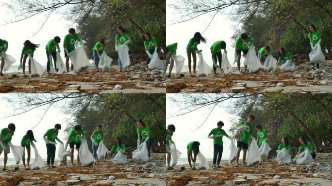 一群穿着绿色t恤的亚洲年轻人志愿者用装满垃圾的塑料袋清理海滩。安全生态概念。4k分辨率。
