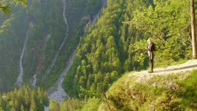 WS女徒步旅行者站在斯洛文尼亚森林悬崖瀑布阳光明媚的顶部