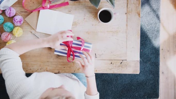 头顶镜头低头看着家里写上生日贺卡和包装礼物的女人