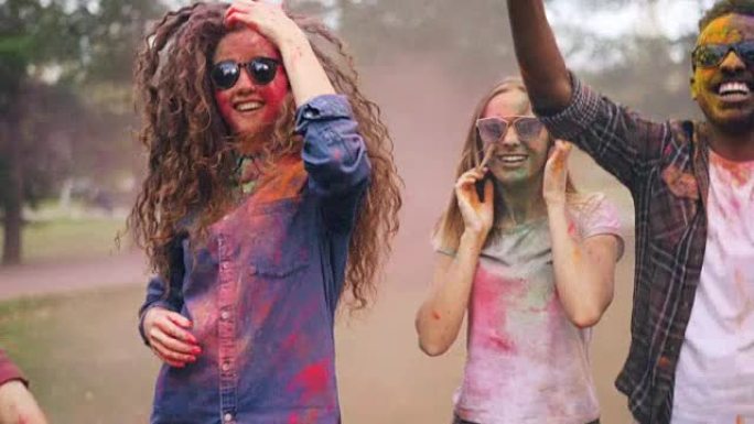 激动的男人和女人在派对上跳舞，上面布满了鲜艳的油漆，享受着传统的印度假日胡里节的乐趣和笑声。自然和文