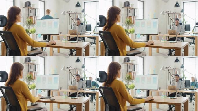 肩膀上: 女性移动软件开发人员坐在办公桌前，使用台式计算机，屏幕上显示智能手机应用程序UI/UX。拥
