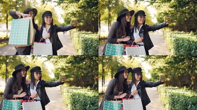 快乐的年轻女性正在用智能手机进行在线视频通话，谈论在秋天的日子里逛街时展示包包和在街上大笑。