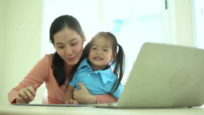 母亲和女儿在家里使用数字平板电脑