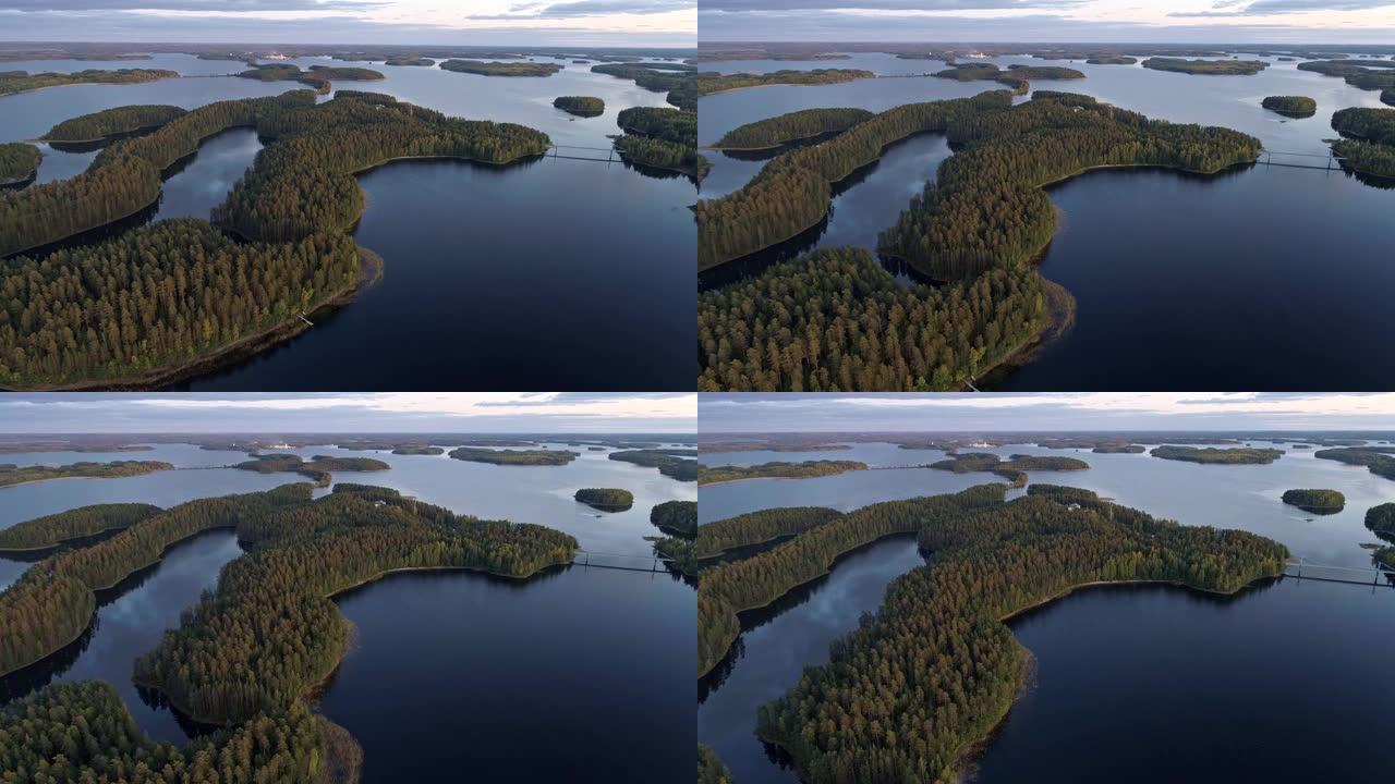 晚上美丽的芬兰莱克兰。在蓝色的湖水和覆盖着常绿松树的岛屿上飞行。空中射击，UHD