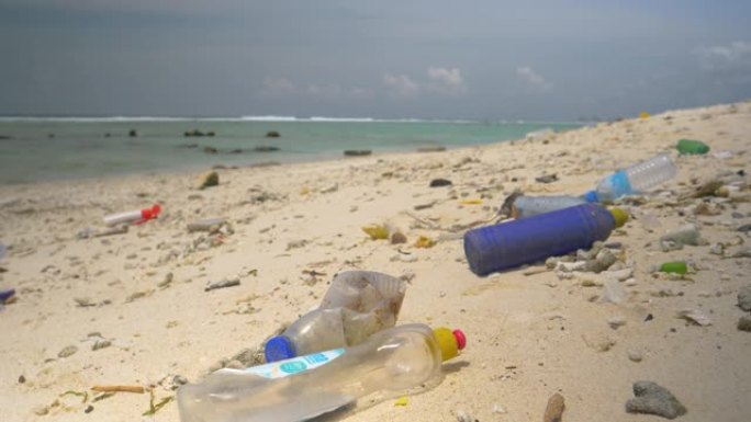 特写: 空的塑料瓶被淹没在热带白色沙滩上。