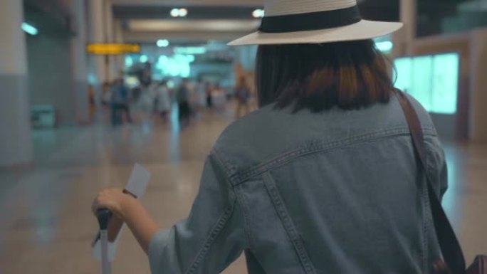 慢动作 -- 快乐的亚洲女人在国际机场登机口登机时，使用手推车或手推车和许多行李走在航站楼大厅。