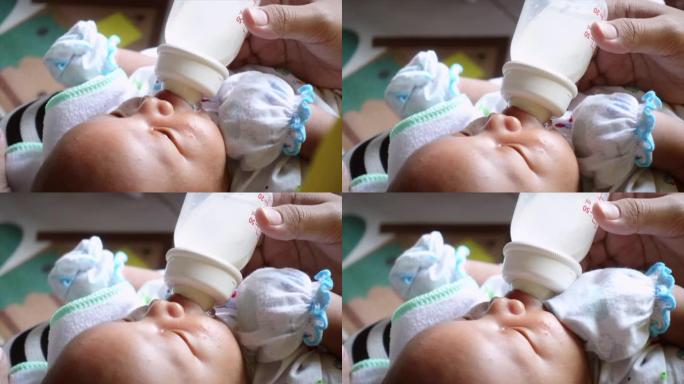 年轻的亚洲母亲在家中卧室用奶瓶喂养男婴
