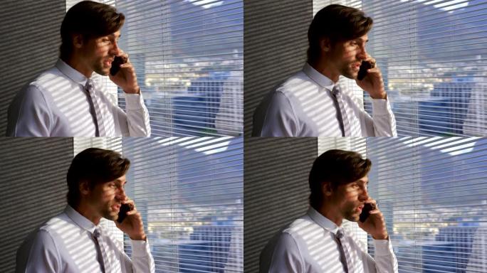 现代办公室4k窗口附近的年轻白人男性高管在手机上聊天的侧视图