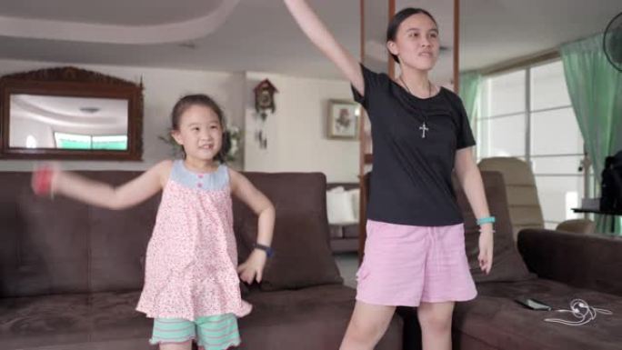 亚洲女孩在电视机前跳舞，在客厅玩电子游戏