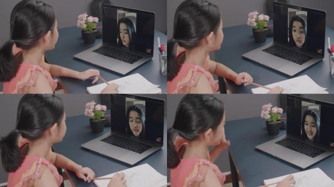 亚洲女孩使用笔记本电脑进行视频通话，并在家里的客厅与姐姐微笑，冠状病毒处于锁定状态，远离距离。技术和