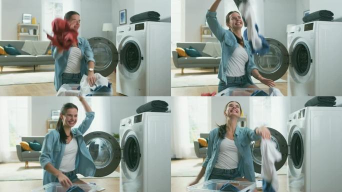 美丽快乐的黑发年轻女子穿着家常牛仔裤的衣服坐在洗衣机旁边。她笑着把洗衣扔到空中。明亮宽敞的客厅，室内