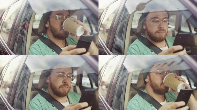 时尚的年轻人坐在汽车上，坐在乘客座位上，使用智能手机，输入消息，通过互联网浏览，喝咖啡。从车外拍摄的