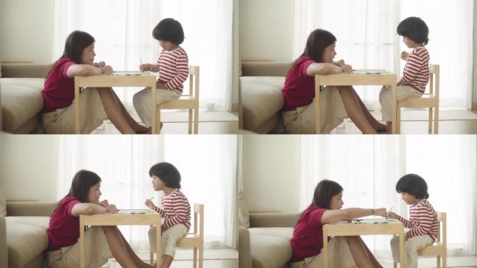 在母亲的帮助下，可爱可爱的亚洲男婴在家做作业。