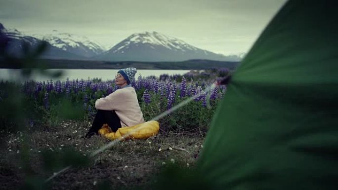女性背包客在盛开羽扇鱼的草地上休息。露营