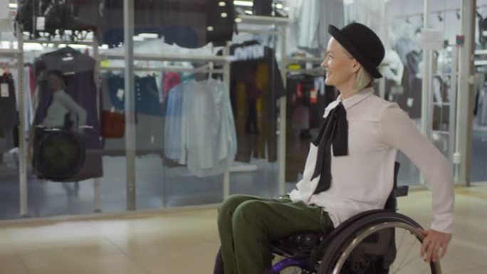 坐在轮椅上的快乐残疾妇女穿过购物中心