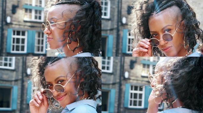 戴着圆形太阳镜的时尚年轻黑人女性转向镜头，头部拍摄，侧视图